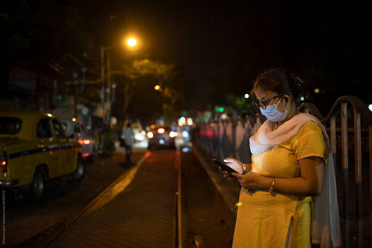 Indian Woman Wearing Mask And Browsing Smartphone In The Street Of Kolkata
