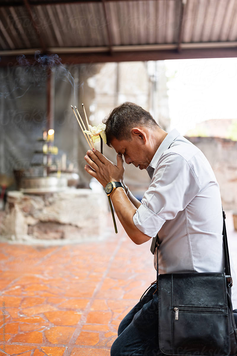 Thai man praying at temple.