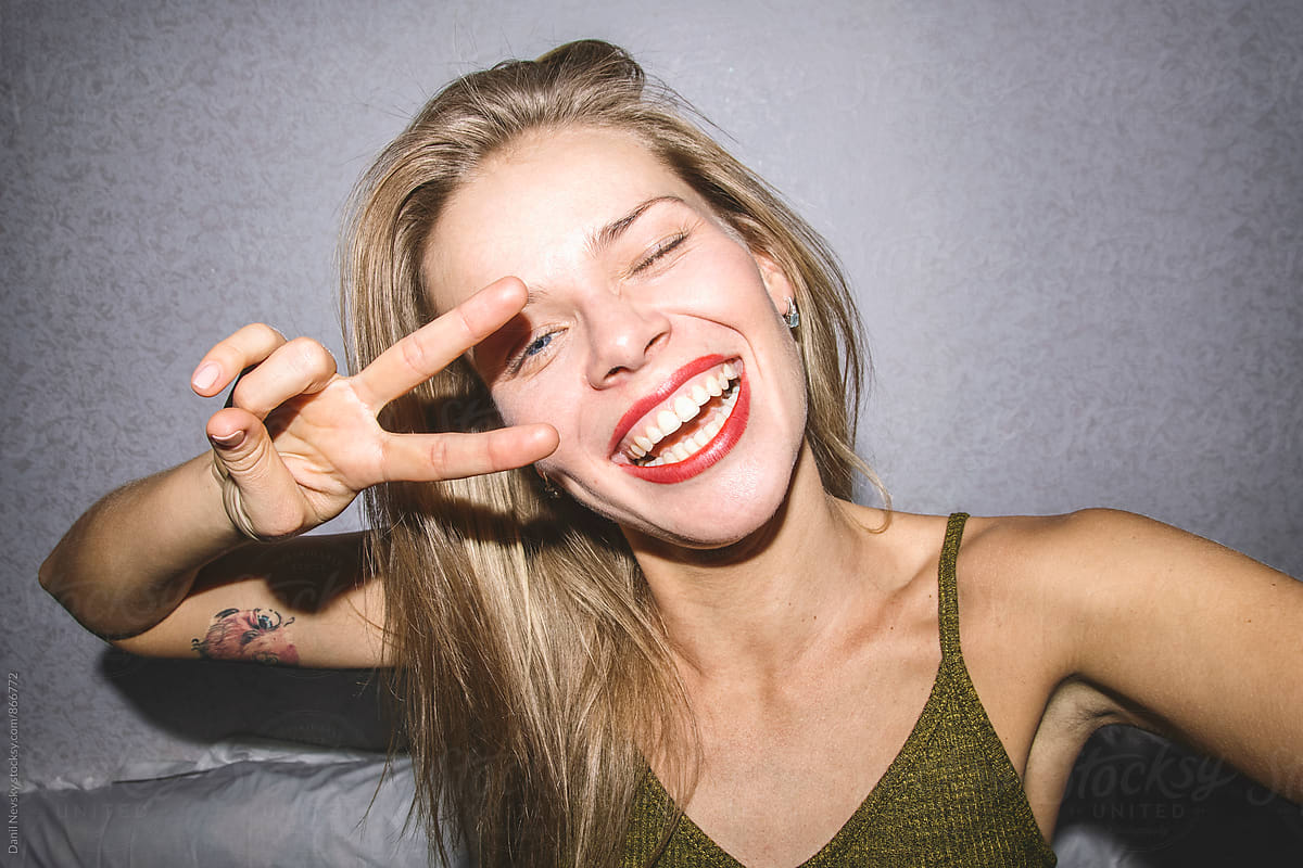Close Up Of Smiling Blonde Woman Showing Peace Sign Del Colaborador De Stocksy Danil Nevsky