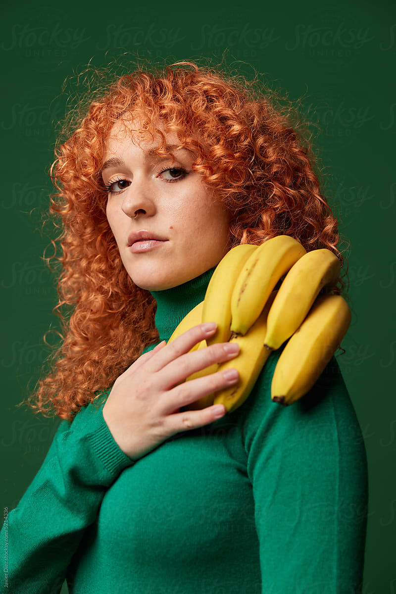 Self assured young ginger woman with banana bunch