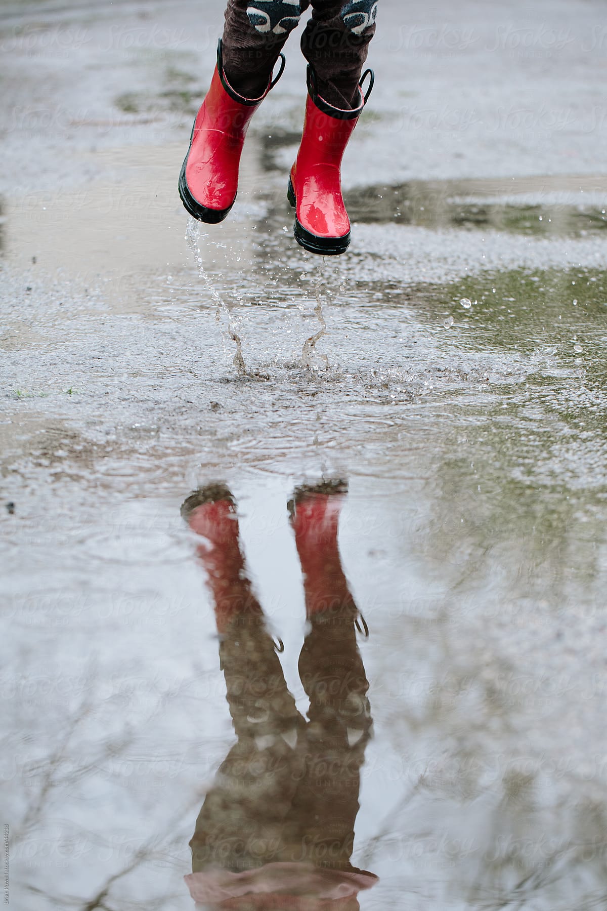 girl jumping in rain puddle