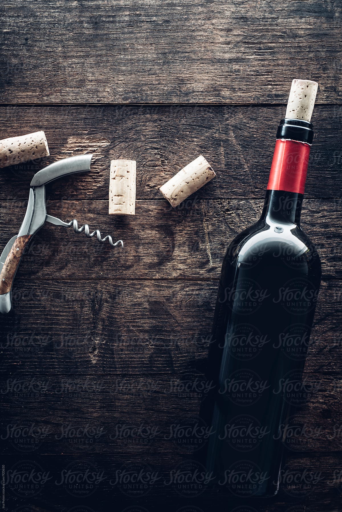 Bottle of wine, corks and grapes on wooden background
