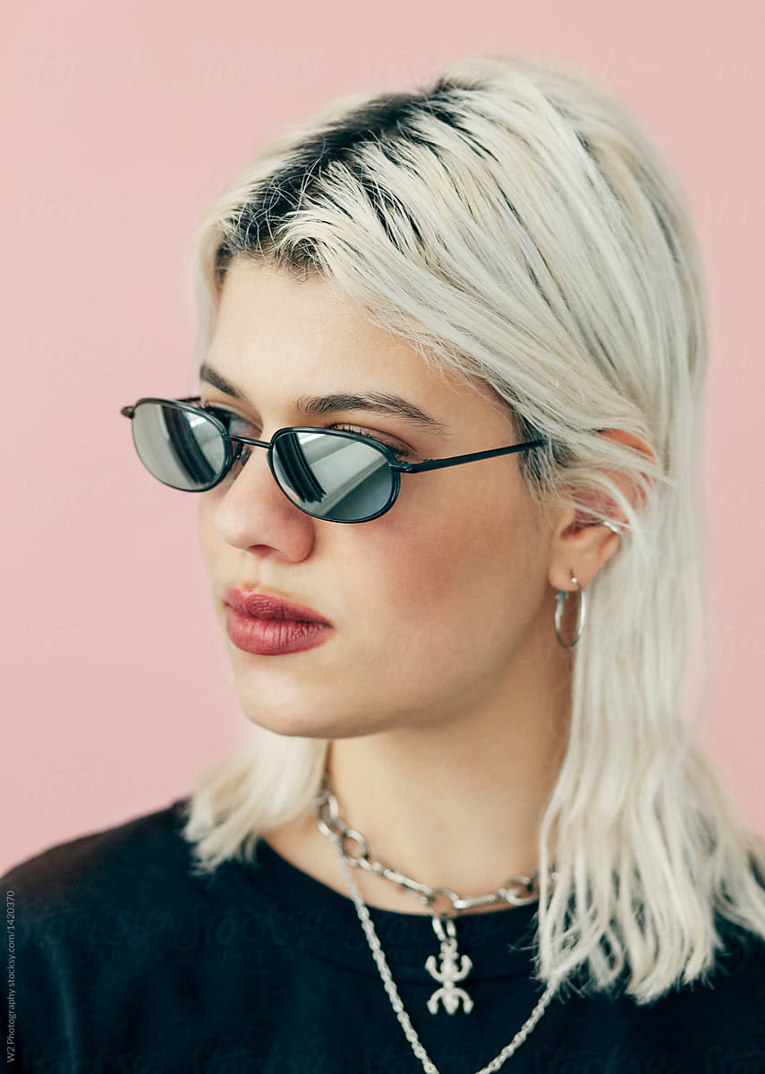 Portrait young woman wearing sunglasses on pink background.