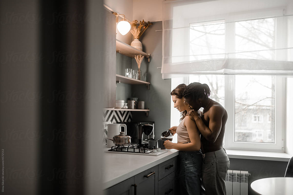 A guy hugs his girlfriend who makes coffee in the morning