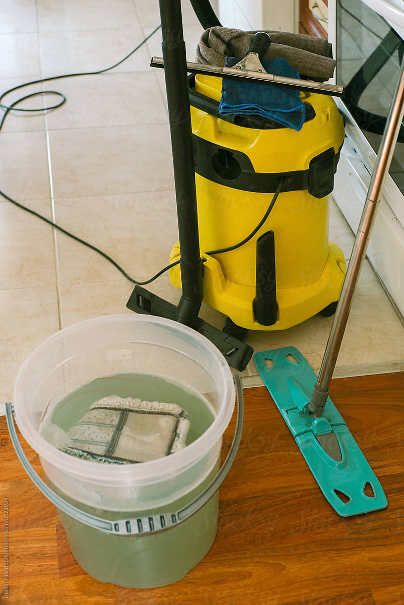 A bucket with a cloth, a mop and a vacuum cleaner.