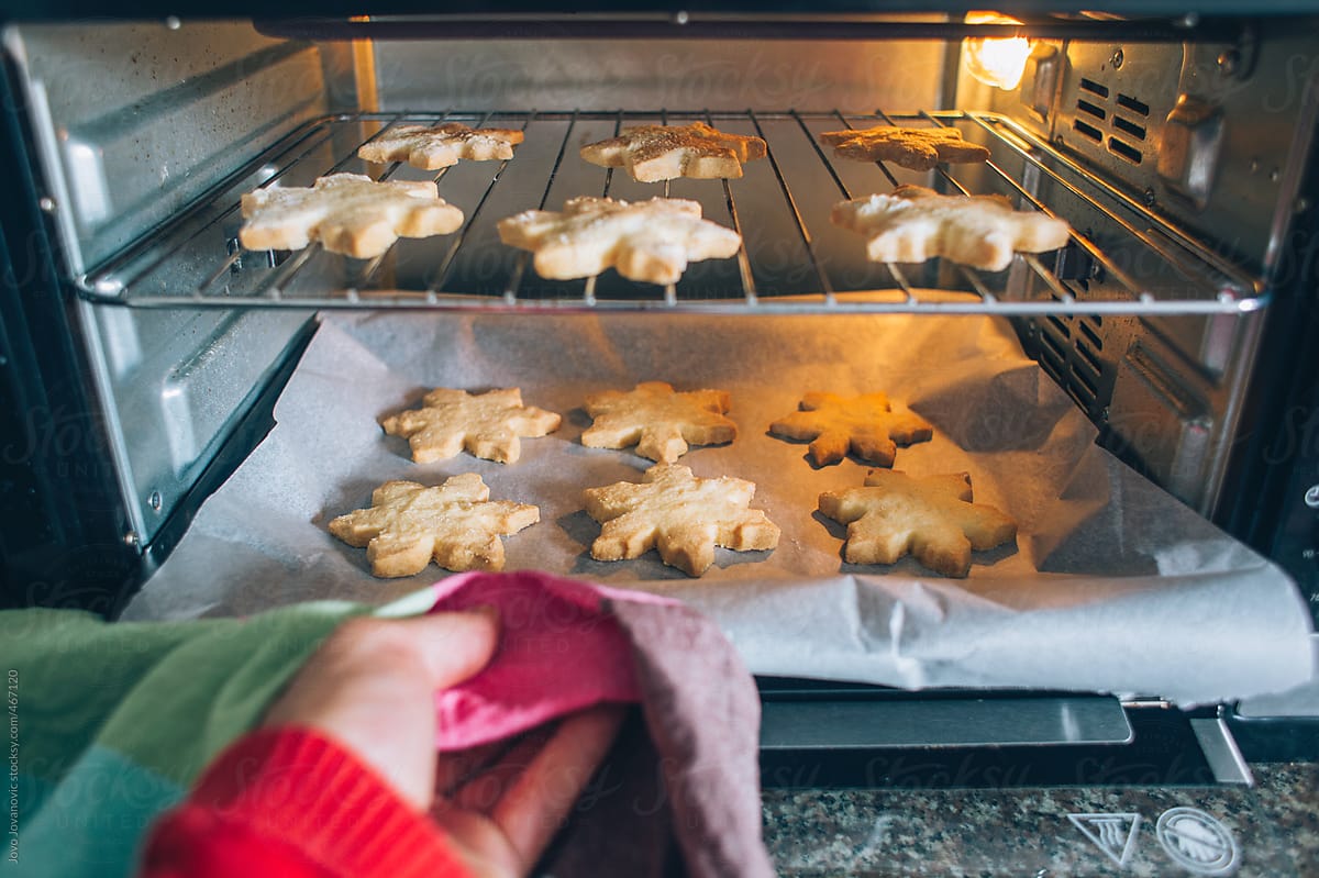 Person taking out Christmas cookies from small oven