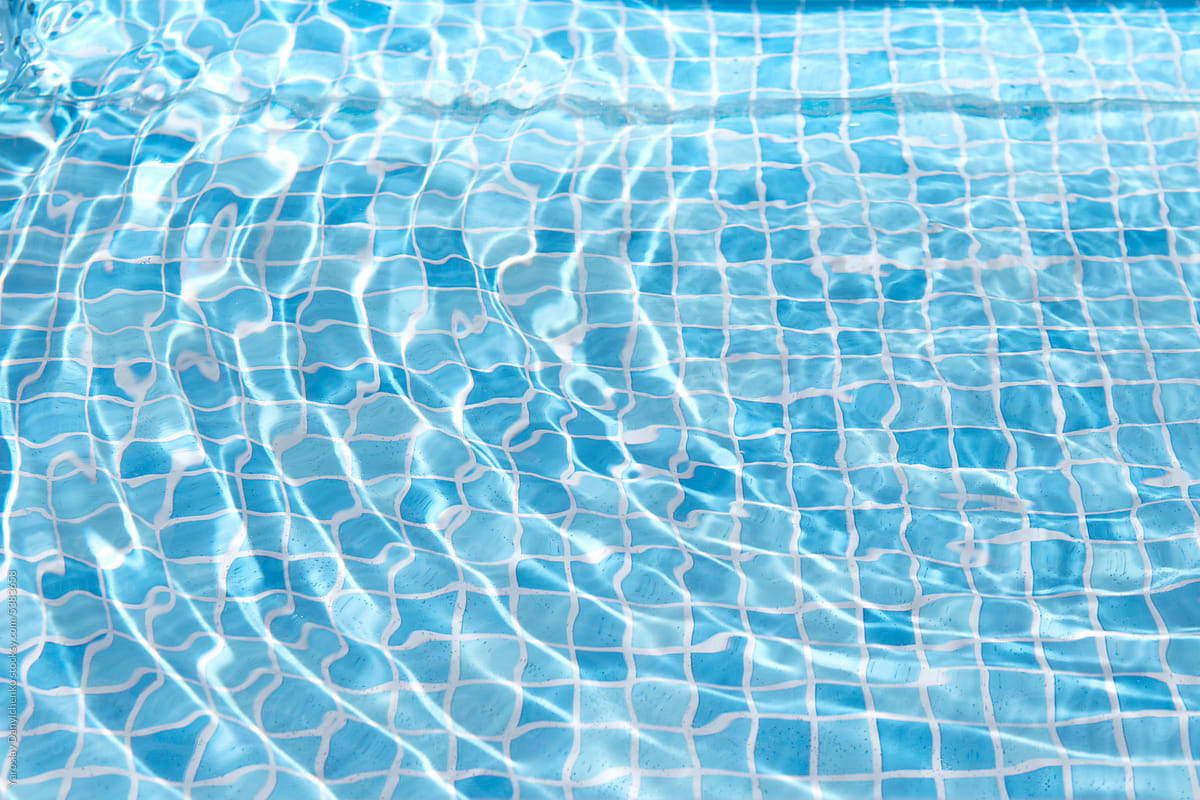 Modern swimming pool with water and blue tiles background.
