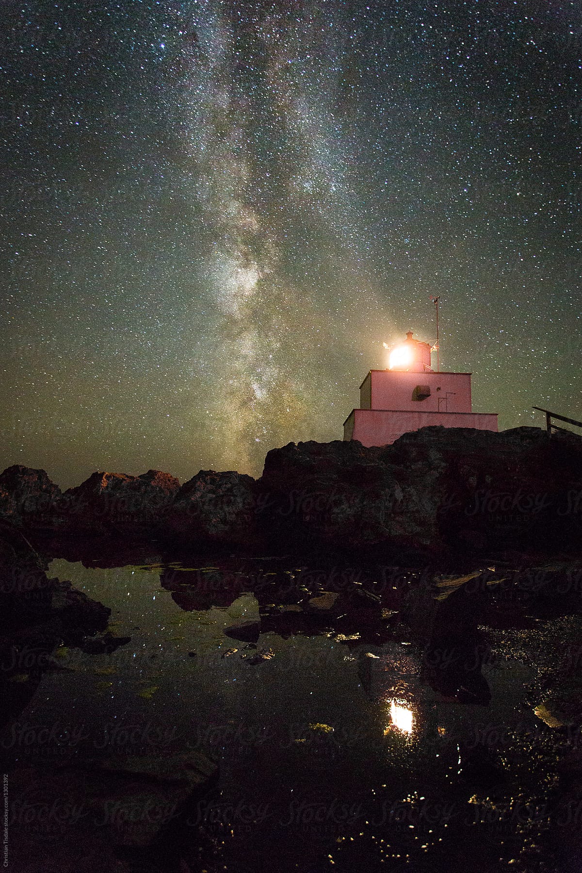 Lighthouse reflecting into a tidal pool with the Milky Way rising up behind it