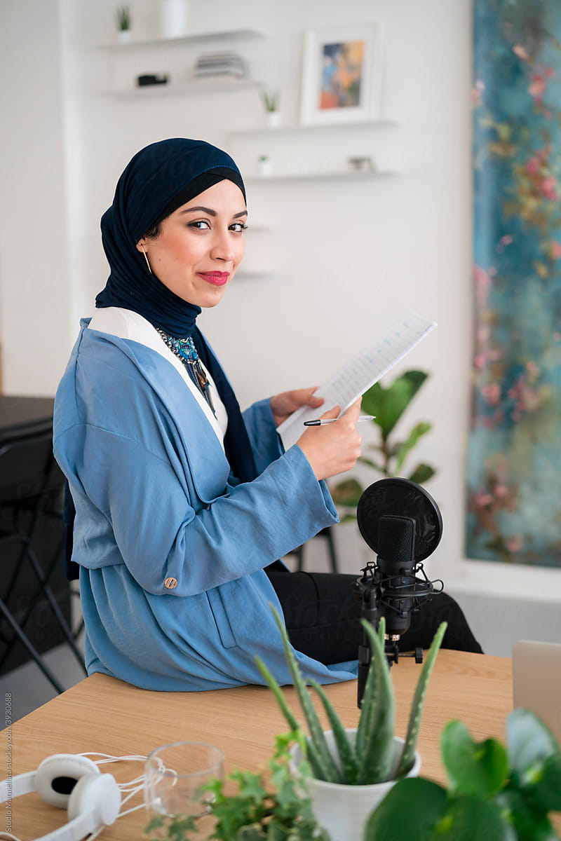 Muslim woman with paper and mic in modern studio