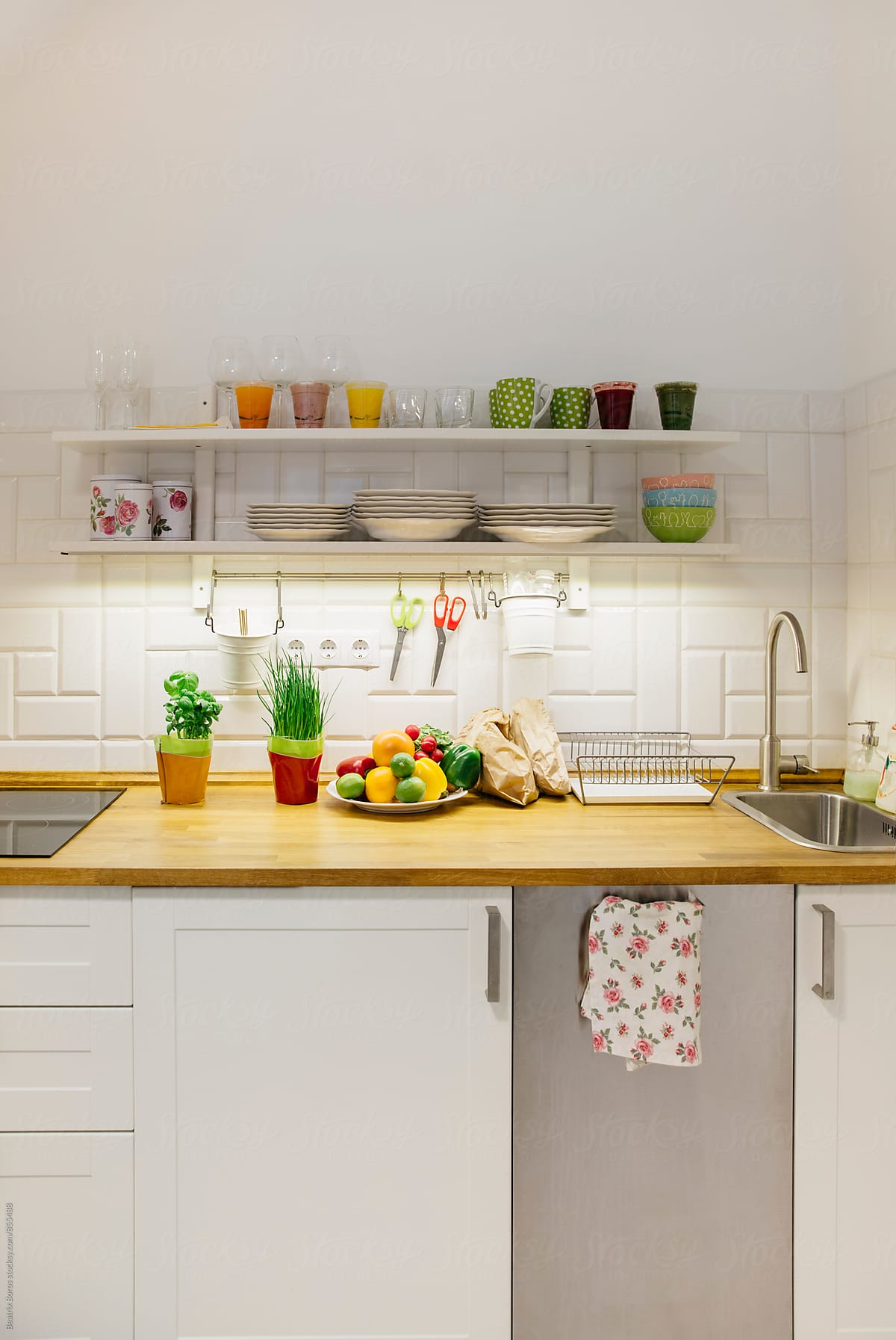 Vertical photo of a small kitchen with raw fruits and veggies on the counter