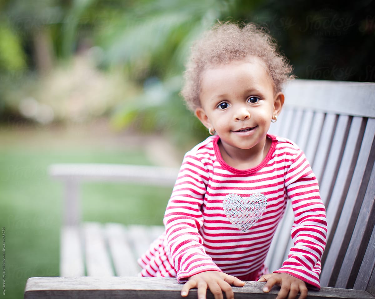 Portrait of toddler sitting on a bench smiling sweetly