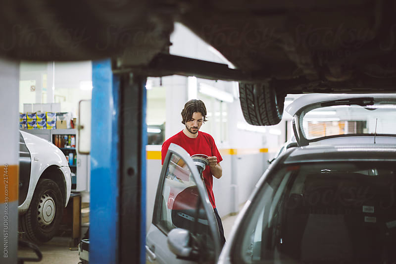 Car mechanic working in auto repair service. by BONNINSTUDIO - Stocksy
