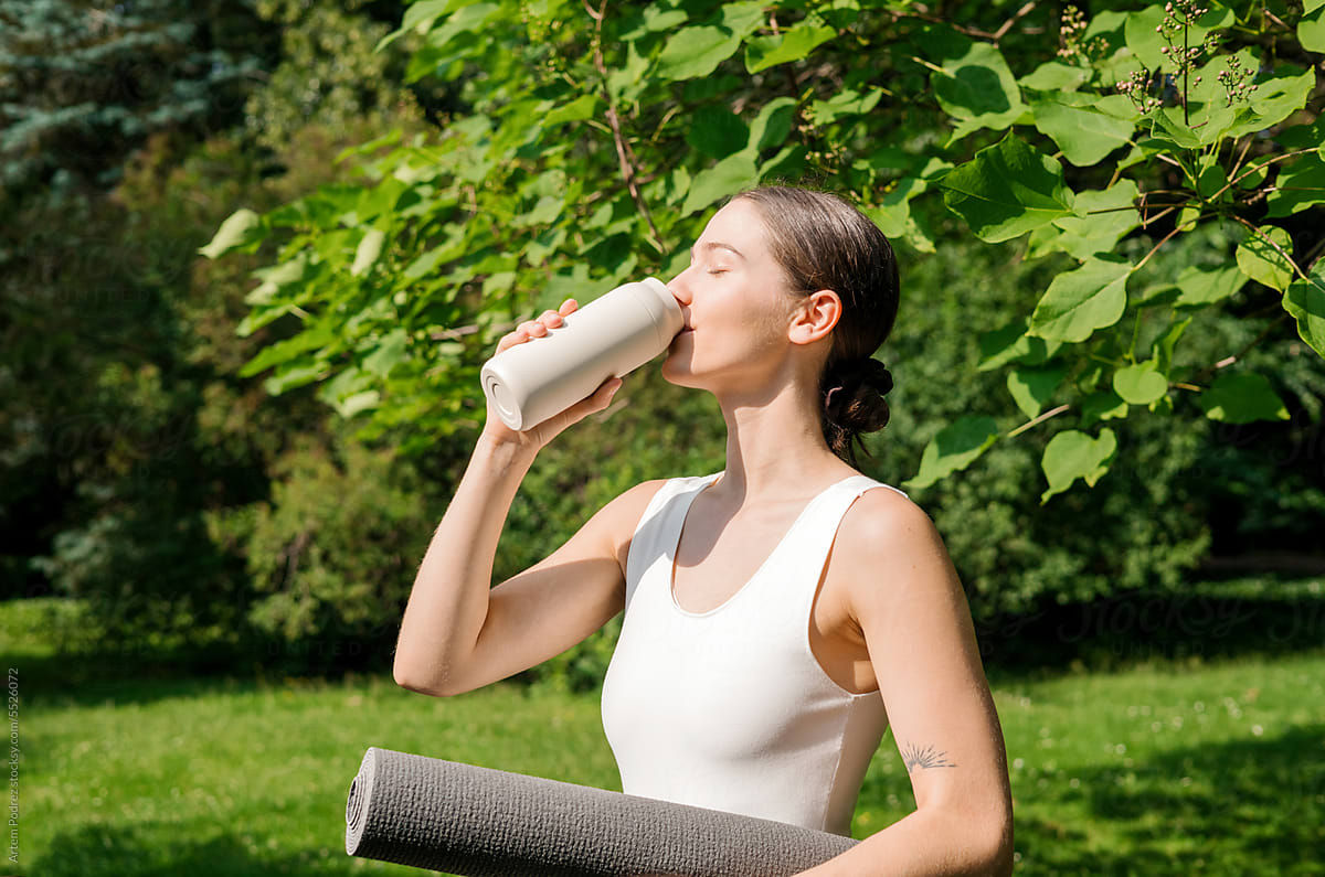 Woman drinks water after morning yoga class