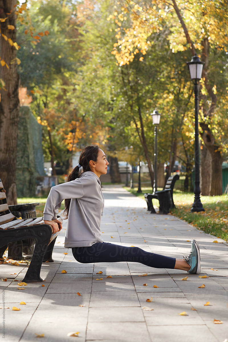 Female athlete doing bench dips on sunlit alley