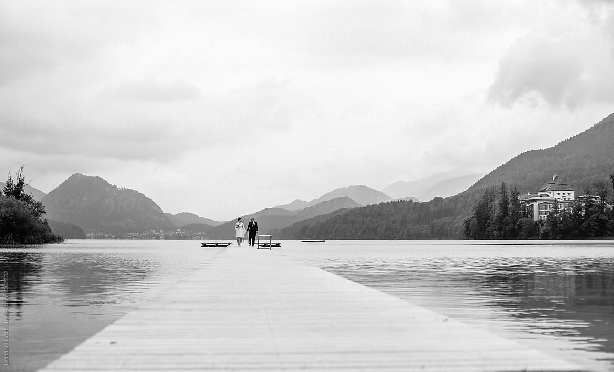 bridal couple walking on a jetty in beautiful lake landscape - black and white
