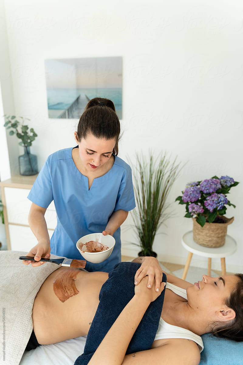 Massage therapist applying slimming treatment to female patient.