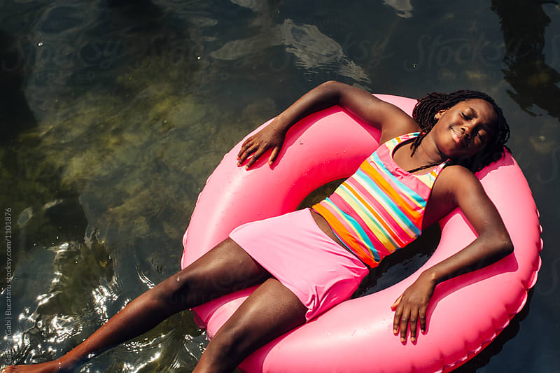 Black girl floating on a pink tube