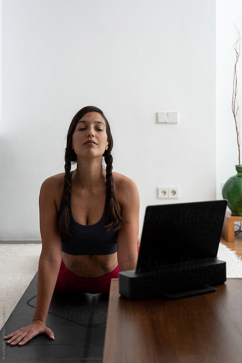 Fit woman following an online yoga session from home
