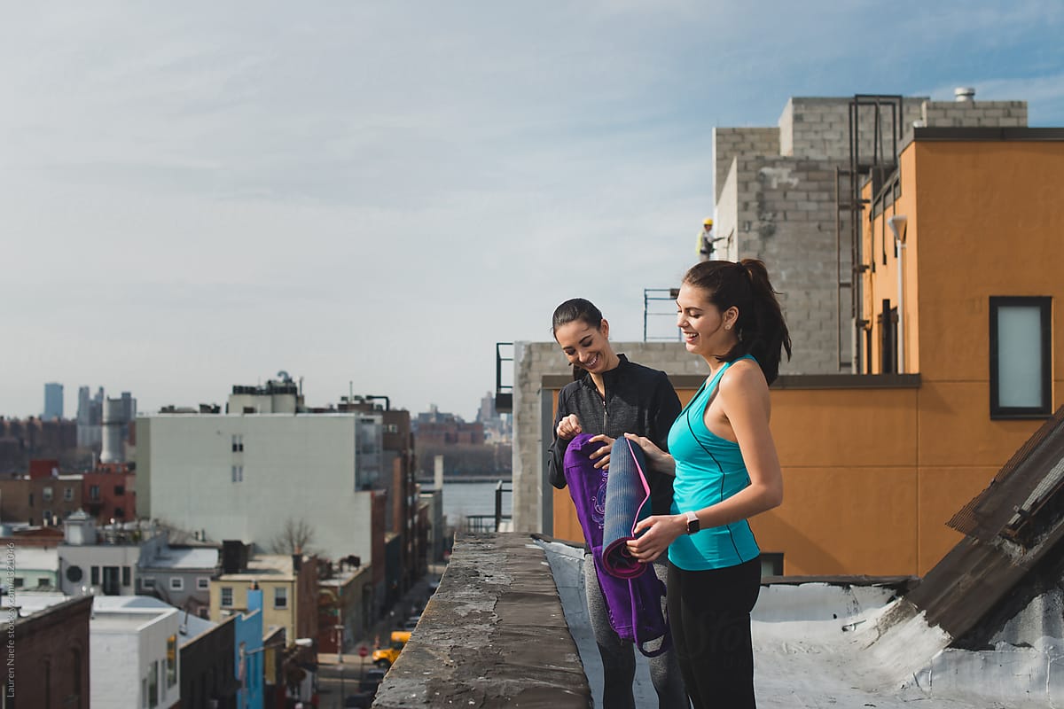 Young woman with yoga mat on rooftop