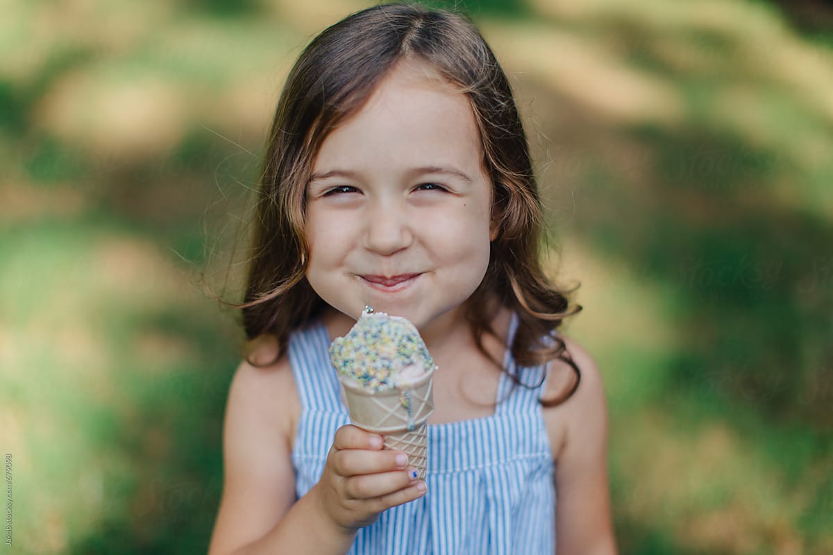 Cute And Happy Young Girl Eating Ice Cream Outside By Stocksy