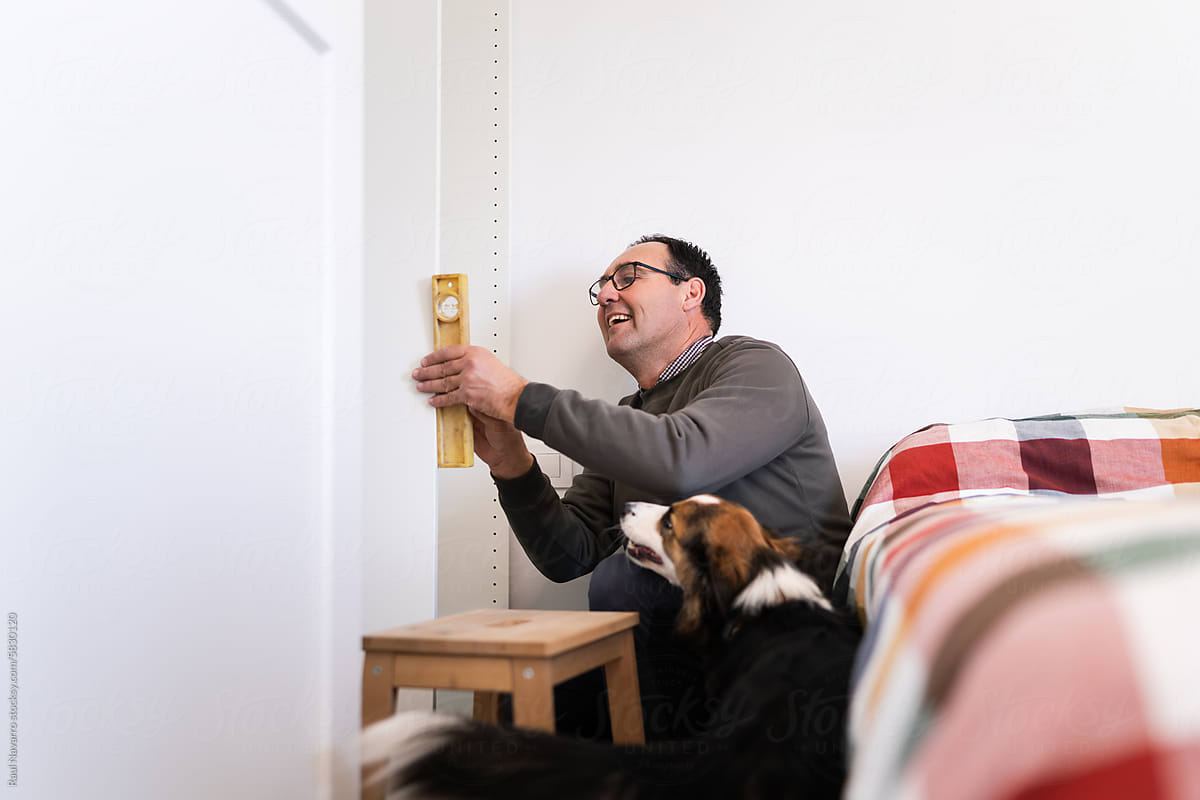 Smiling man assembling a piece of furniture with his dog