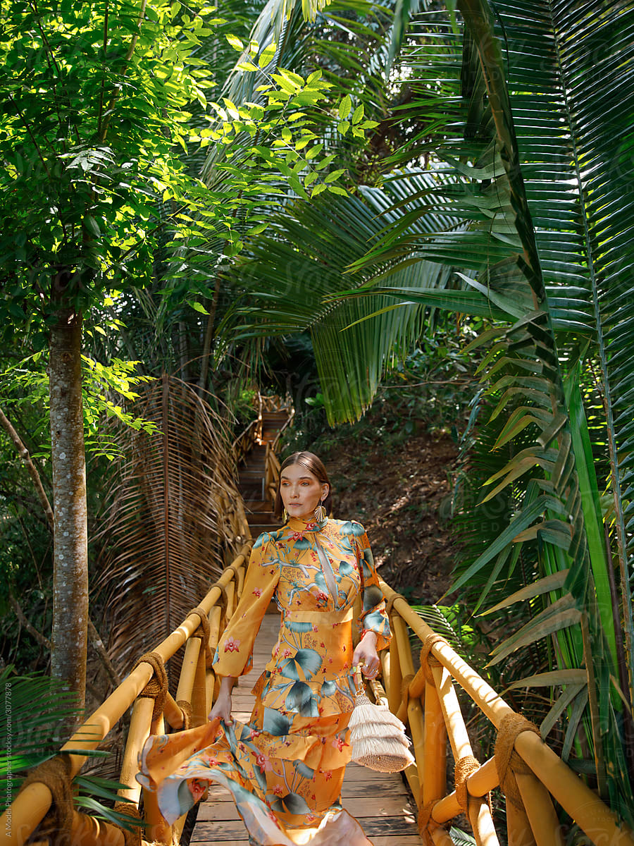 Stylish woman in dress on path in tropical forest.