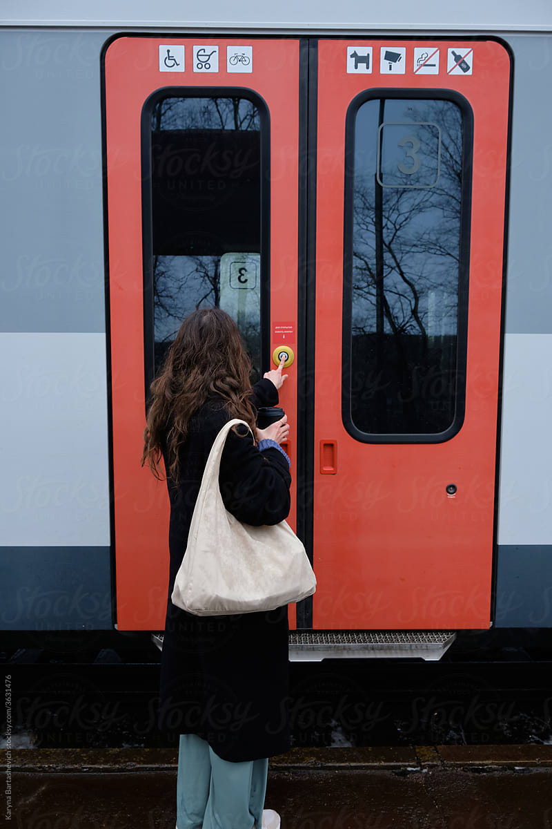 girl in stylish clothes with a bag on her shoulder at the station in front of the train