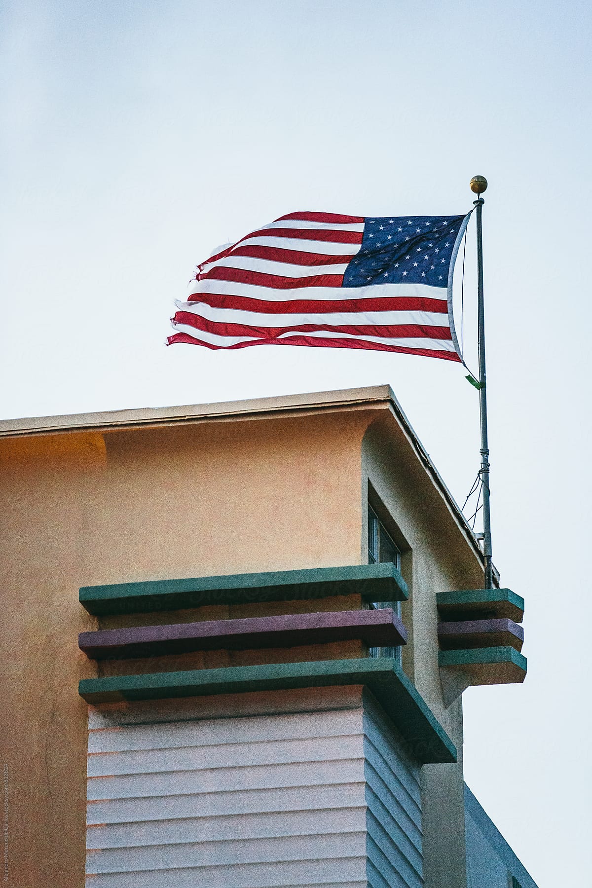 View of a an american flag flying in the wind on top of a building
