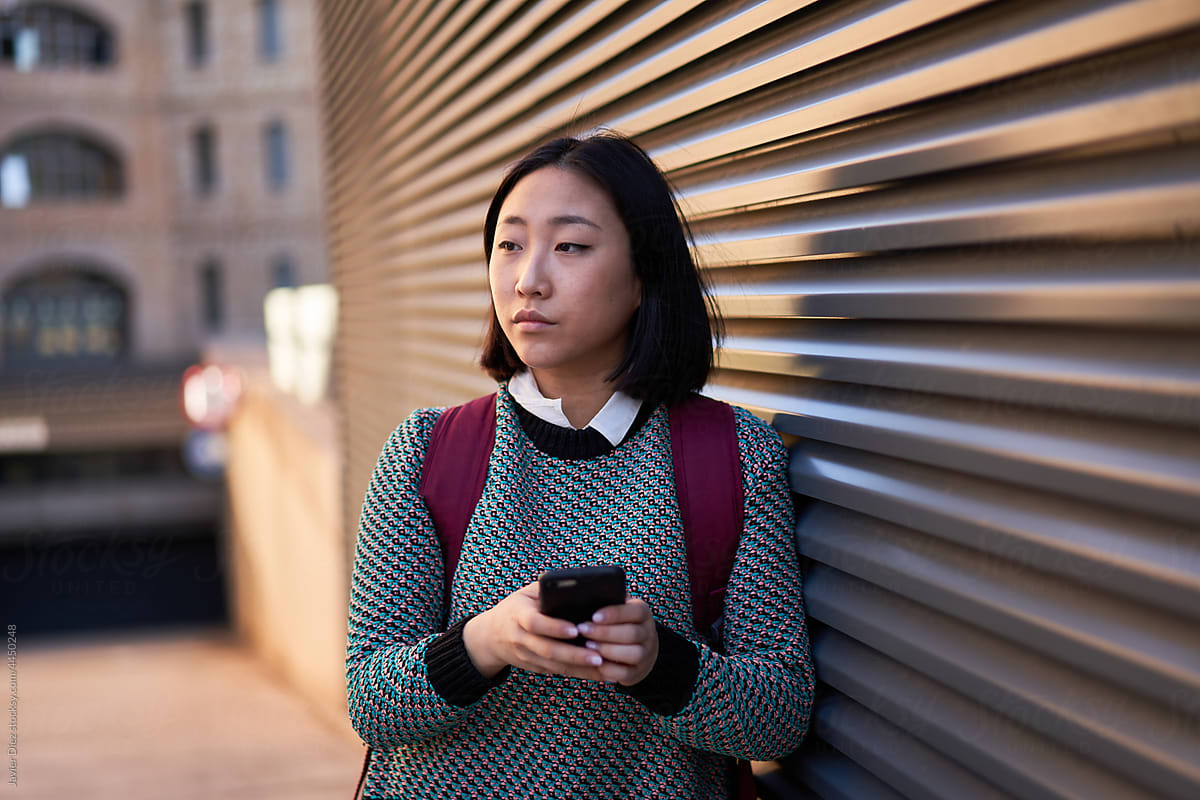 Female student using smartphone on street