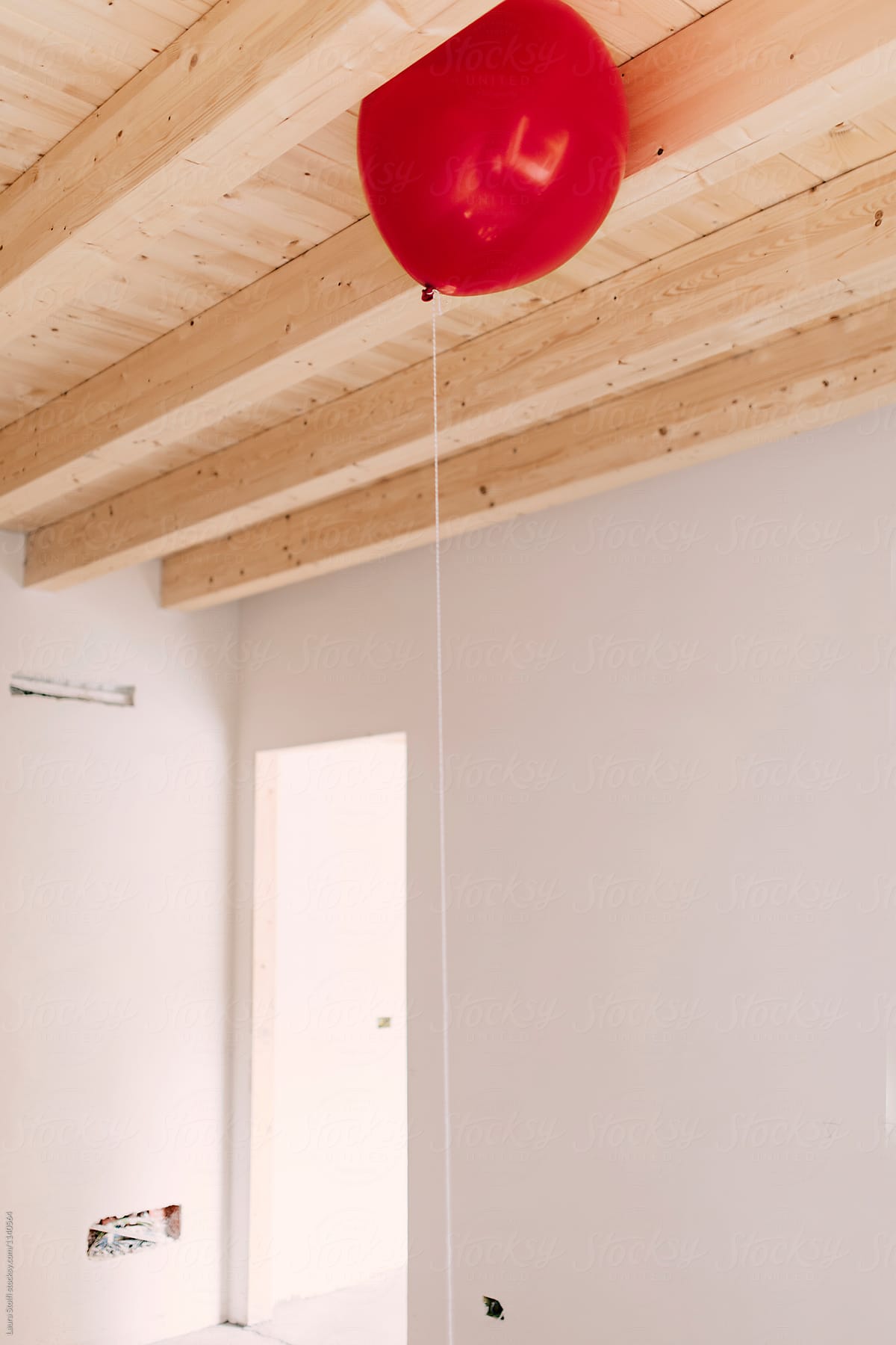 Single red balloon under wooden ceiling