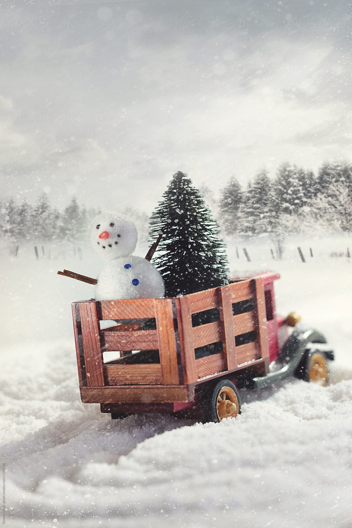 Small toy truck with trees and snowman in snow storm