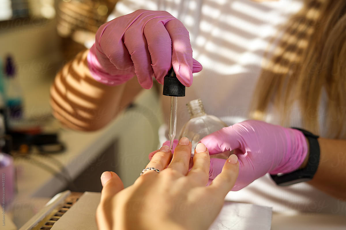 A manicurist applies oil on woman\'s nails and cuticles in beauty salon