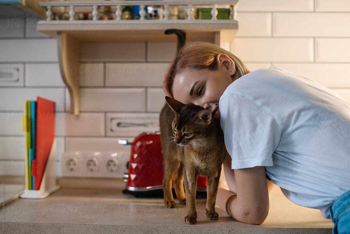 Sweet portrait of a girl with her cat at the kitchen