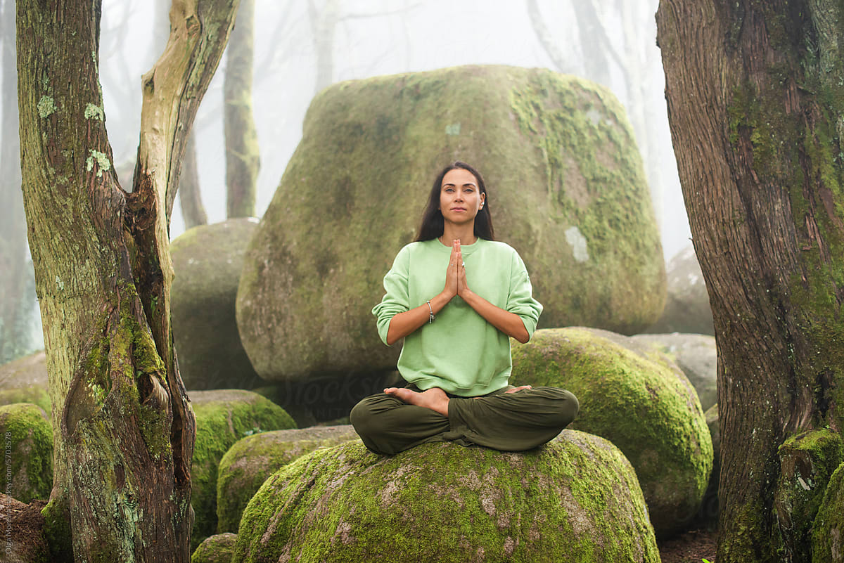 Woman practicing gratitude while sitting on a rock in the forest