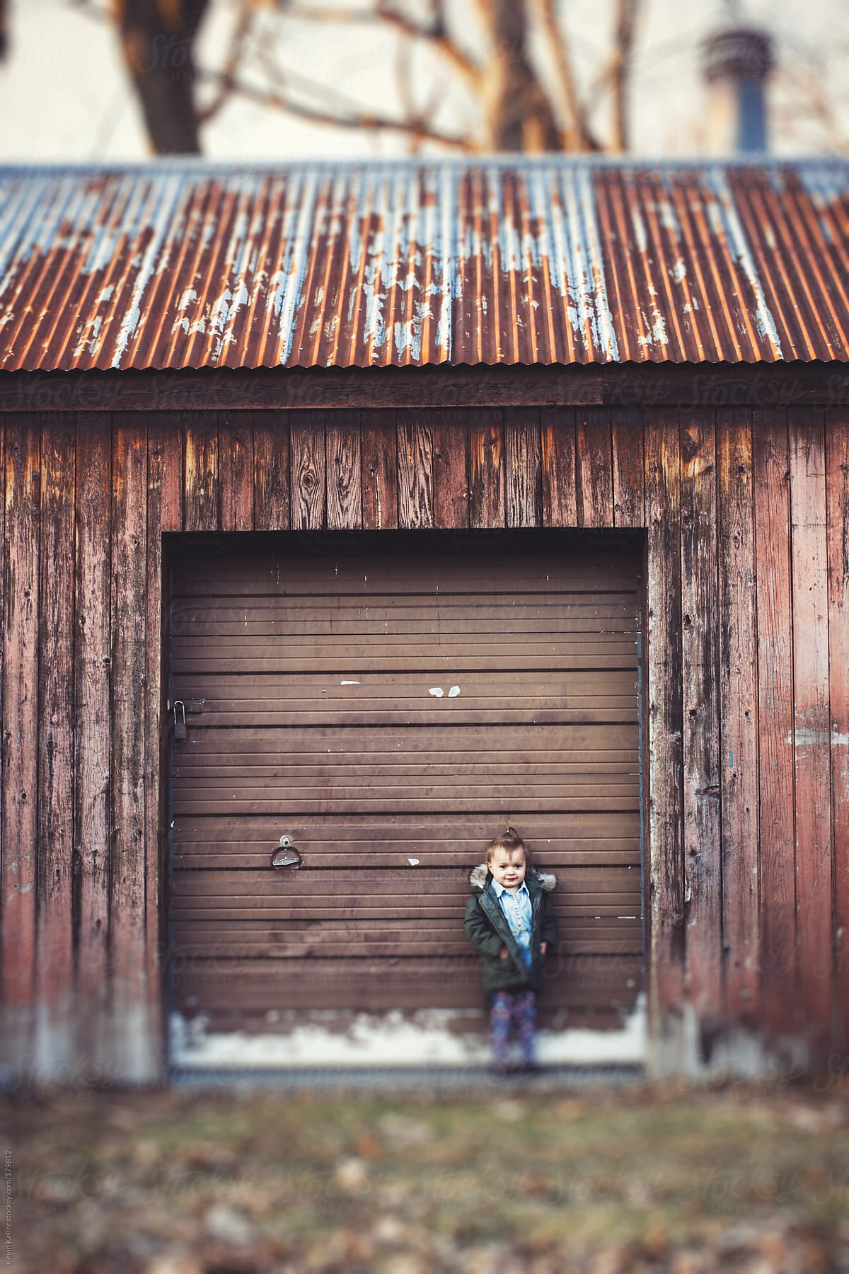 Toddler Girl Standing Against an Old Garage Door