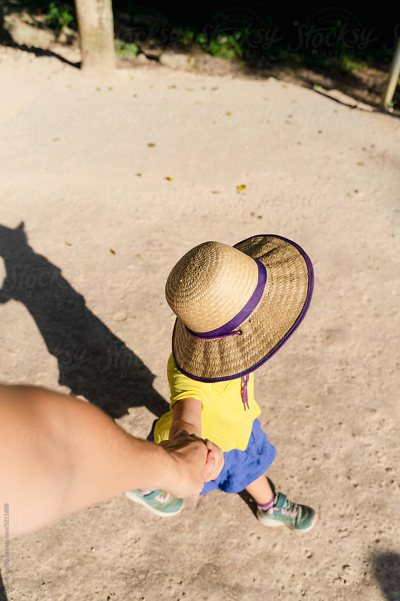 Travel with kids. Little girl with sun hat holding mum\'s hand