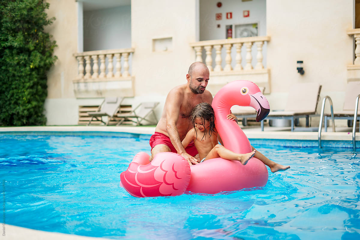 Father with daughter on inflatable flamingo