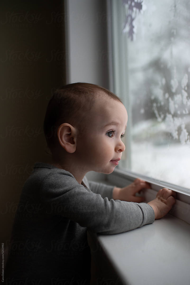 Toddler Watching Snow Fall Outside the Window