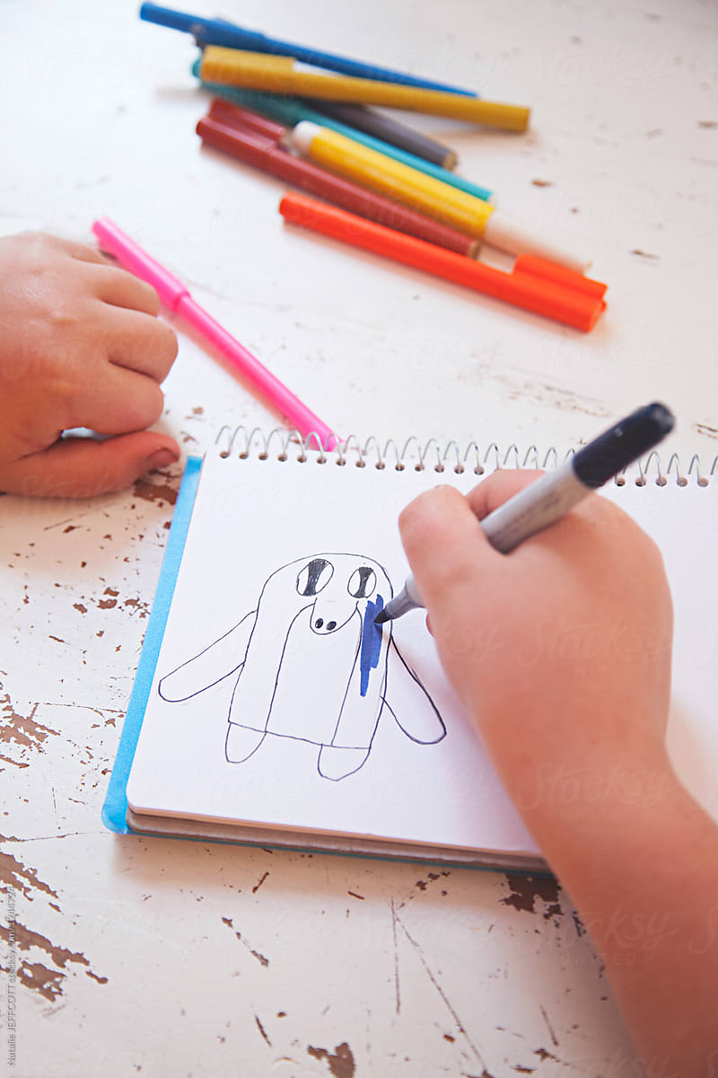 A young boy drawing a picture of a penguin