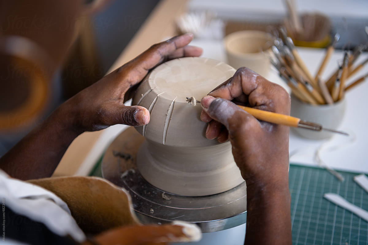 Closeup of a woman\'s hands working on pottery at her desk
