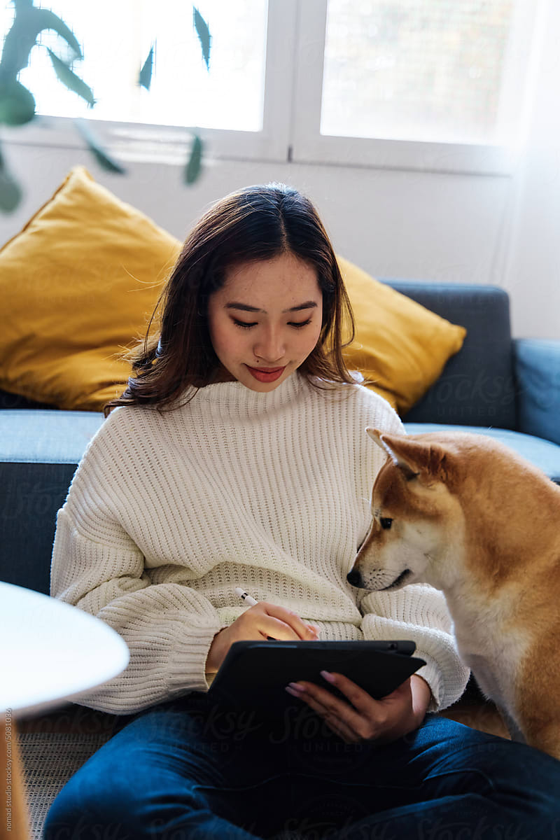 Woman using a digital tablet with her dog at home.