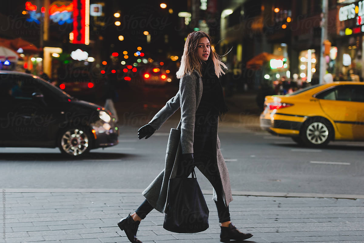 Young woman walking in the city at night