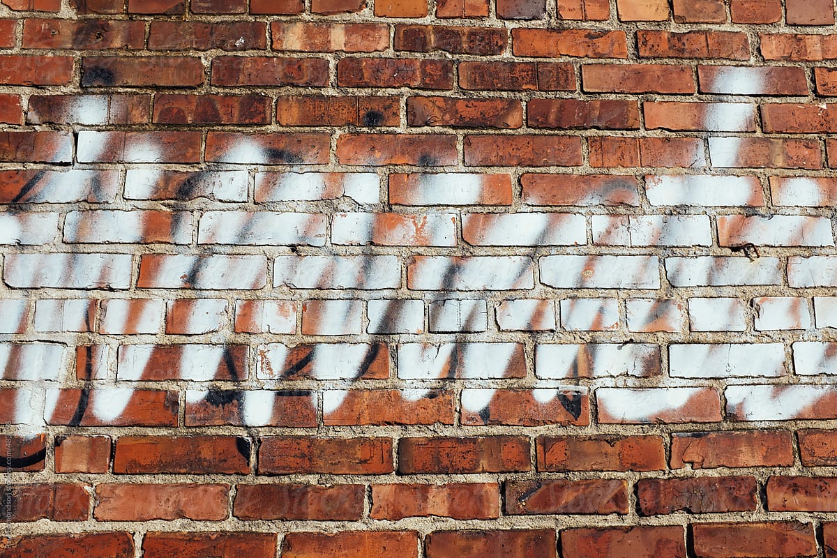 Spray paint covering graffiti on old brick wall
