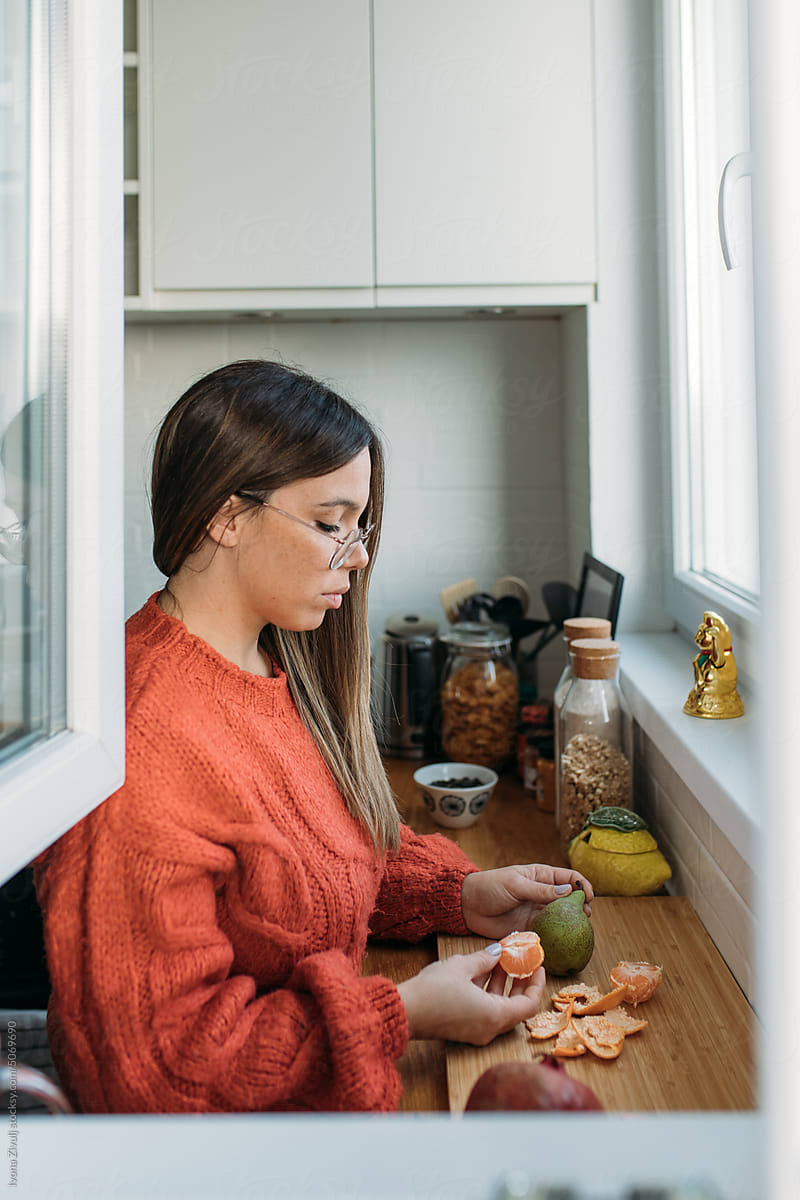 Woman Peeling Orange in Her Kitchen