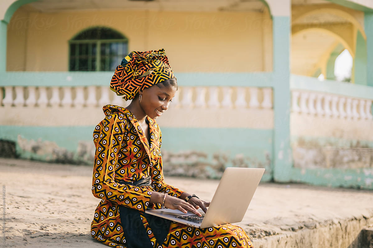 Stylish black lady working on netbook in village