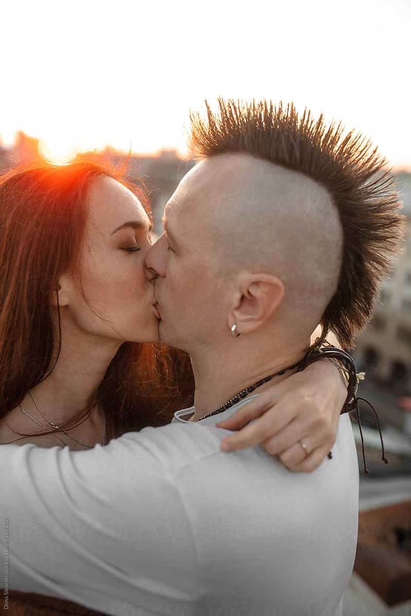 A guy with a mohawk is kissing his girlfriend