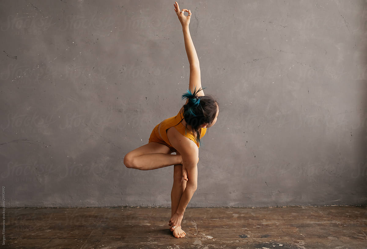 Slim ethnic woman doing yoga near shabby wall