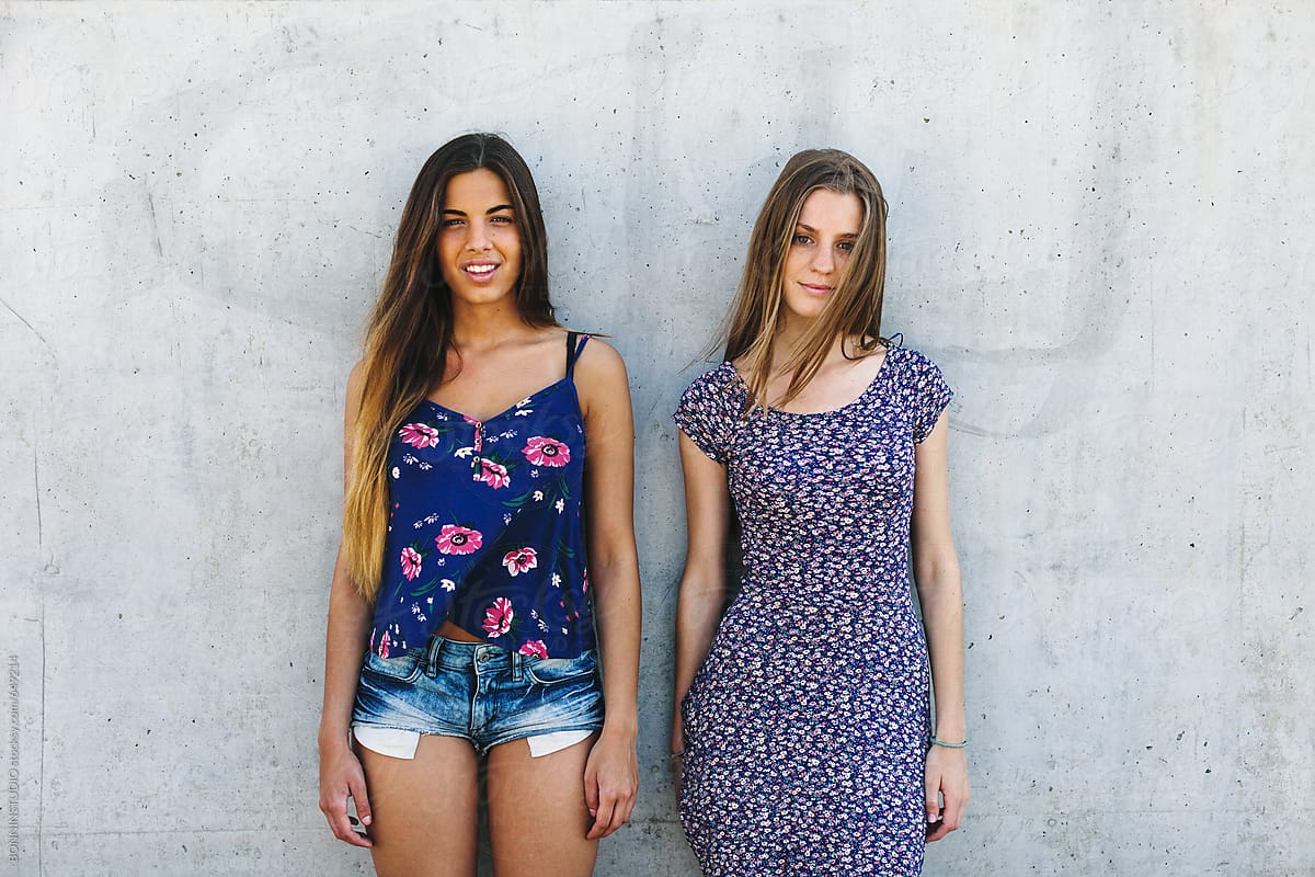 Young Women Wearing Summer Clothes Standing In Front Of A Wall