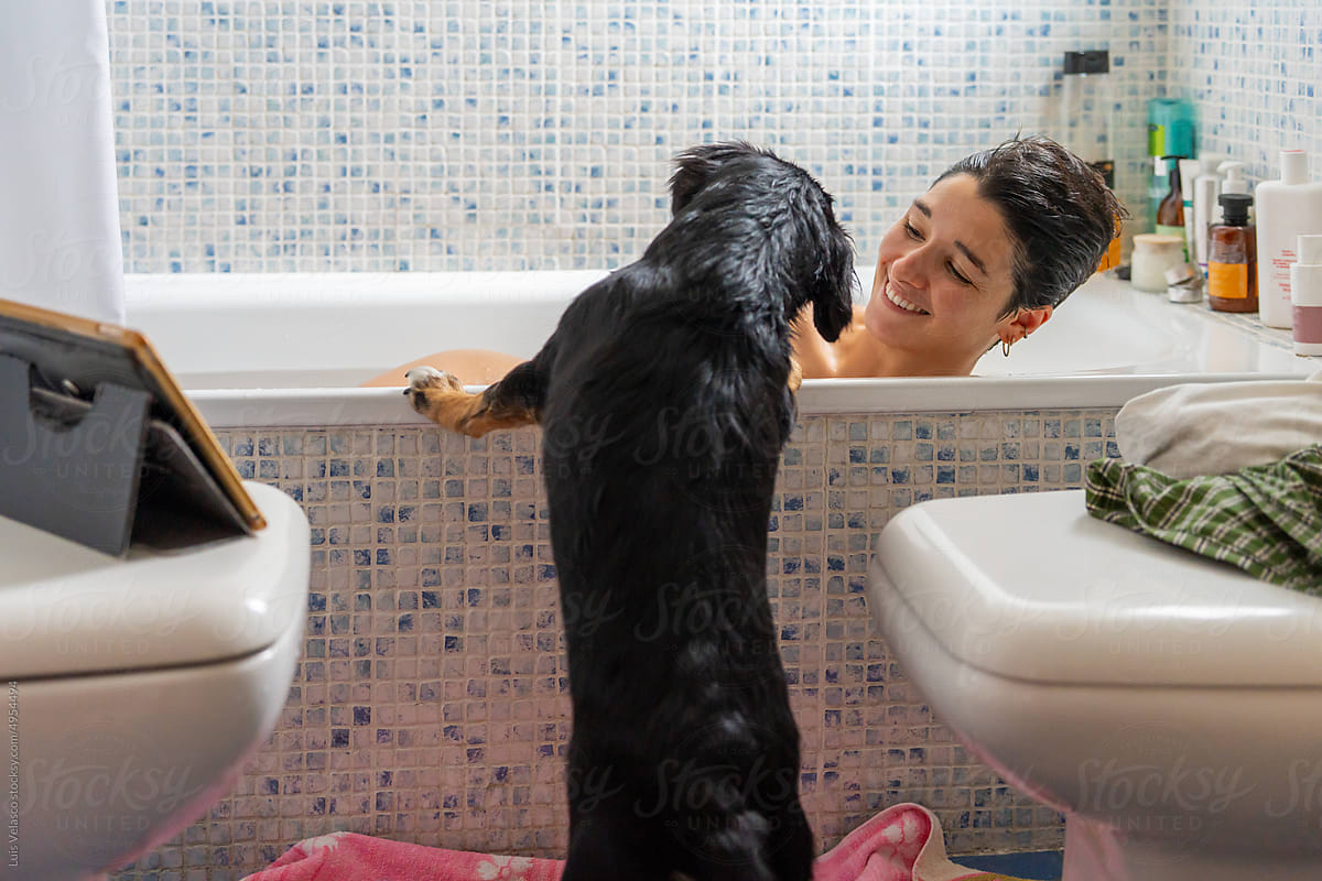 Girl Taking A Bath Next To Her Little Dog.