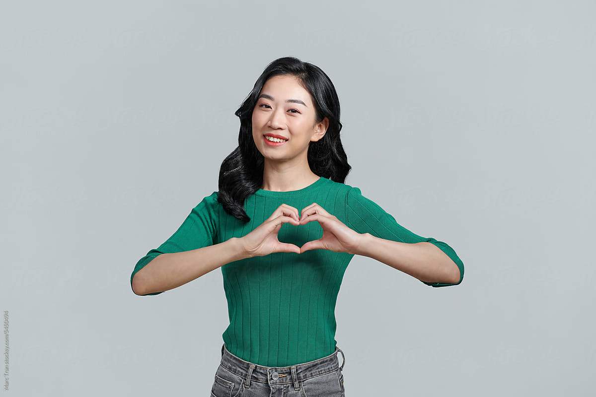Romantic young girl doing a heart gesture with her fingers